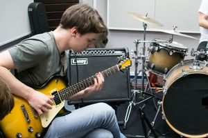 Mateusz Biliński grający na gitarze w pracowni muzycznej