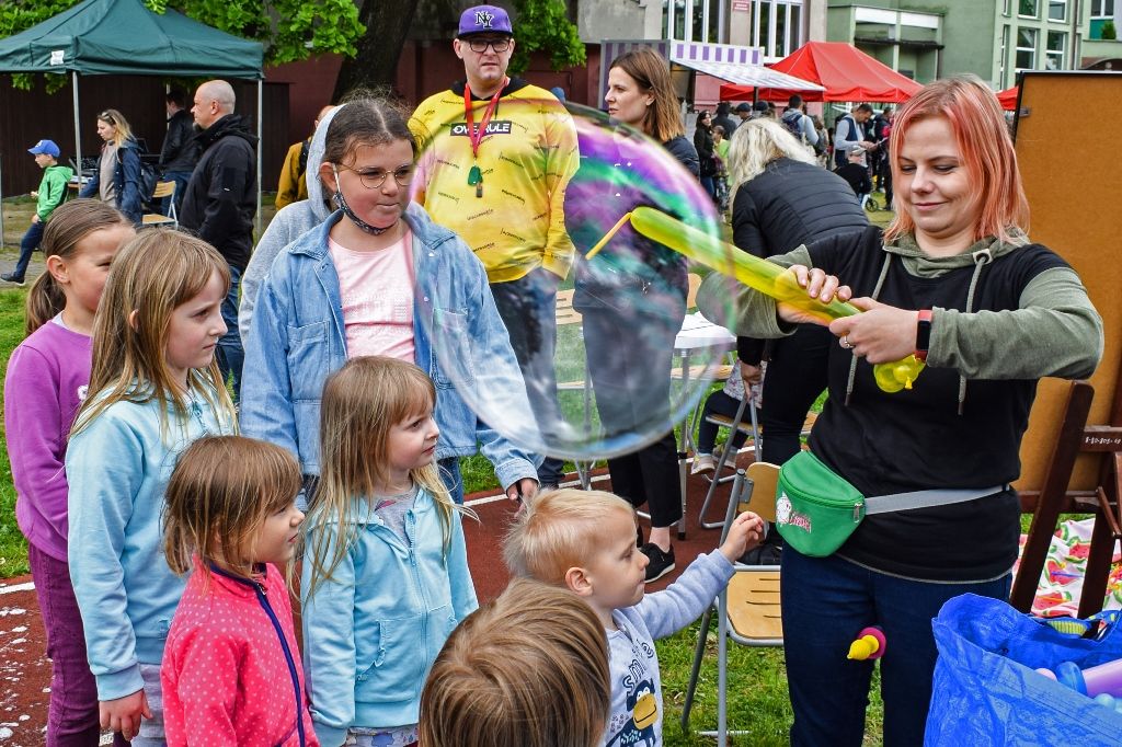 festyn, instruktorka pokazuje gromadzie dzieci jak puszczać wielkie bańki mydlane