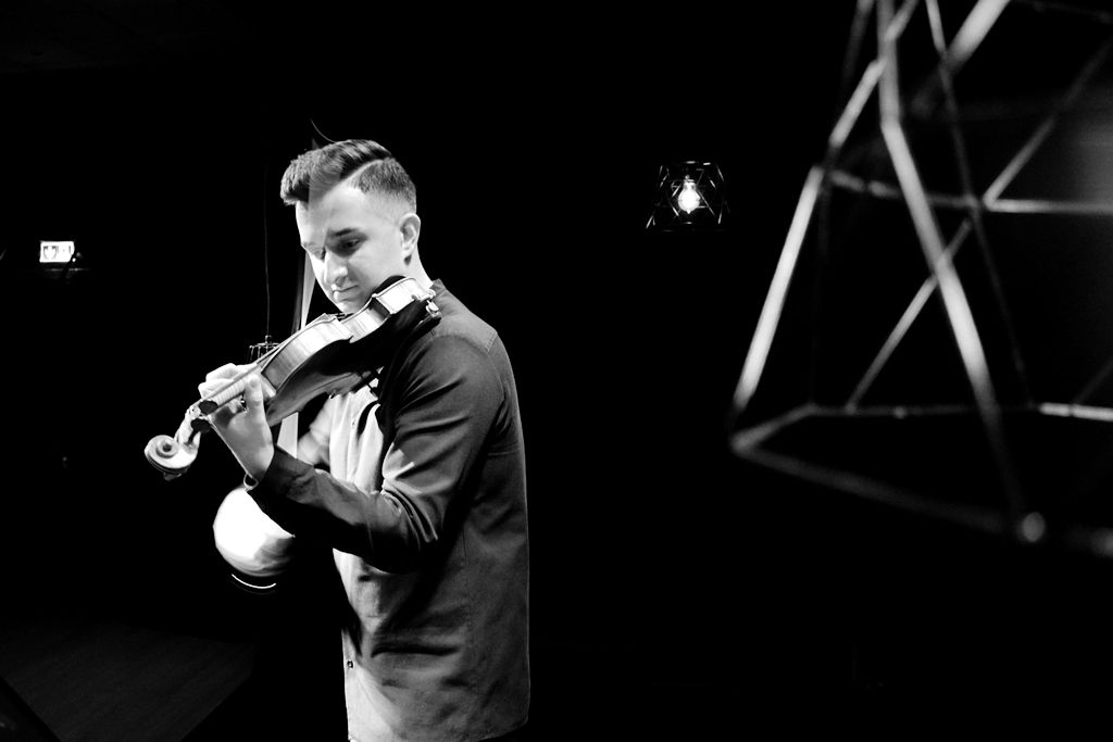 Bartłomiej Fraś gra na skrzypcach podczas koncertu na scenie