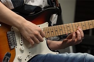 Mateusz Biliński grający na gitarze w pracowni muzycznej